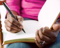 Close-up of hands writing in a journal.