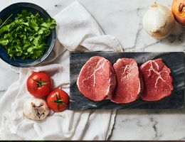 Lean beef on a black marble cutting board.