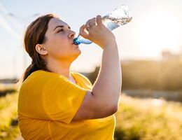 A woman drinks from a disposable plastic water bottle.