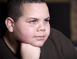 Closeup of a child resting his chin on his fist.