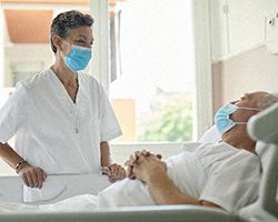 A nurse smiles at a man in a hospital bed.