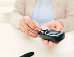 Hands insert a strip into a glucose meter