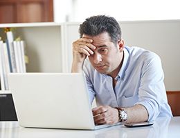 A man sitting at his desk with his computer looked stressed.