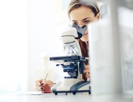 A woman looks into a microscope