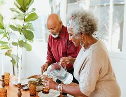 An older couple dishes up a healthy meal together.