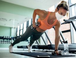 Woman holding dumbells in both hands while in plank position.