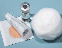 A small bandage, cotton ball and vaccine vial.