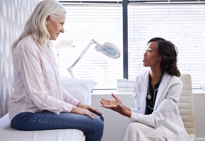 Patient Sitting On Exam Table Consulting With A Doctor During A Health Screening