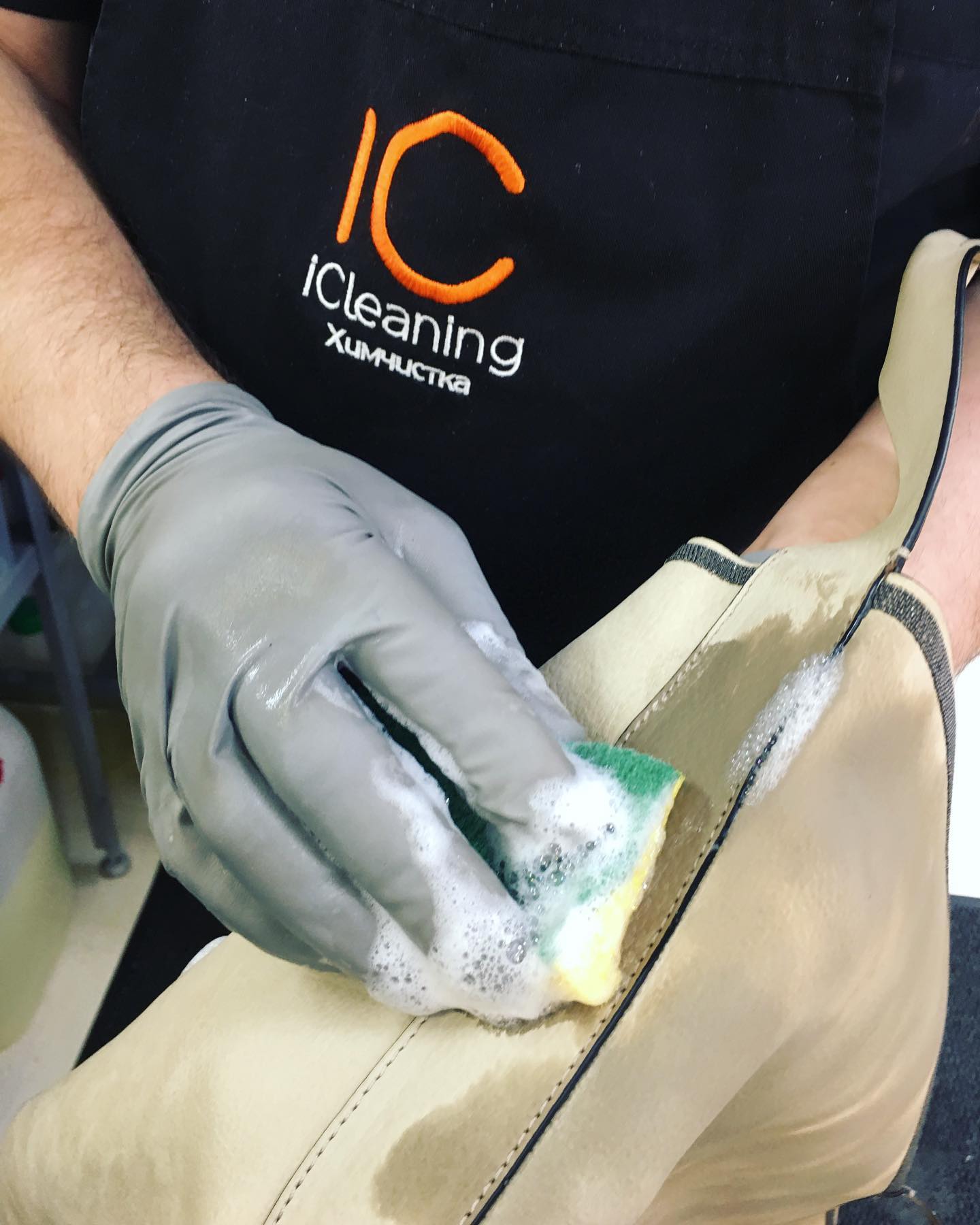 Мастер iCleaning вручную очищает светлое кожаное изделие профессиональными средствами