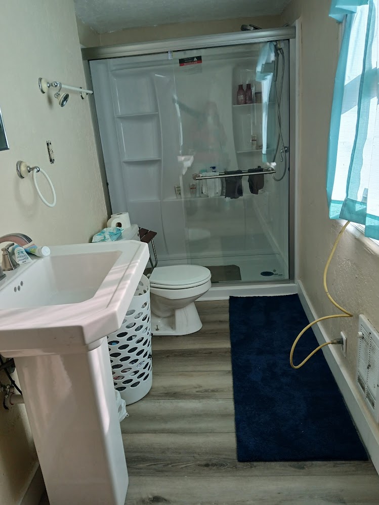 remodeled bathroom with new sink, shower, flooring, and paint