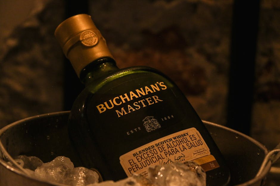 An image of a Buchanan's Master whisky bottle resting in a bucket filled with ice. The bottle is prominently featured, showcasing its label and branding, creating a luxurious and classy vibe suitable for an upscale occasion or advertisement.