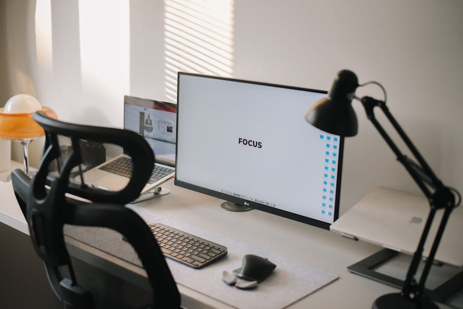 A minimalist workspace featuring a large monitor displaying the word 