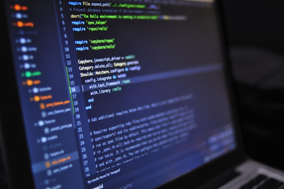 A close-up of a laptop screen displaying a code editor with highlighted syntax and various lines of code. The screen shows text files and folder structures on the side panel, indicating software development in progress. The setting suggests a programming or coding activity.