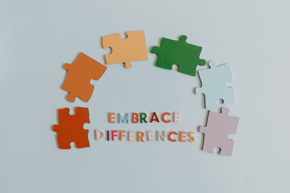 The image features seven colorful puzzle pieces arranged in a semi-circle around the phrase 'EMBRACE DIFFERENCES' in multicolored letters on a light background. This image conveys a message of inclusivity and diversity.