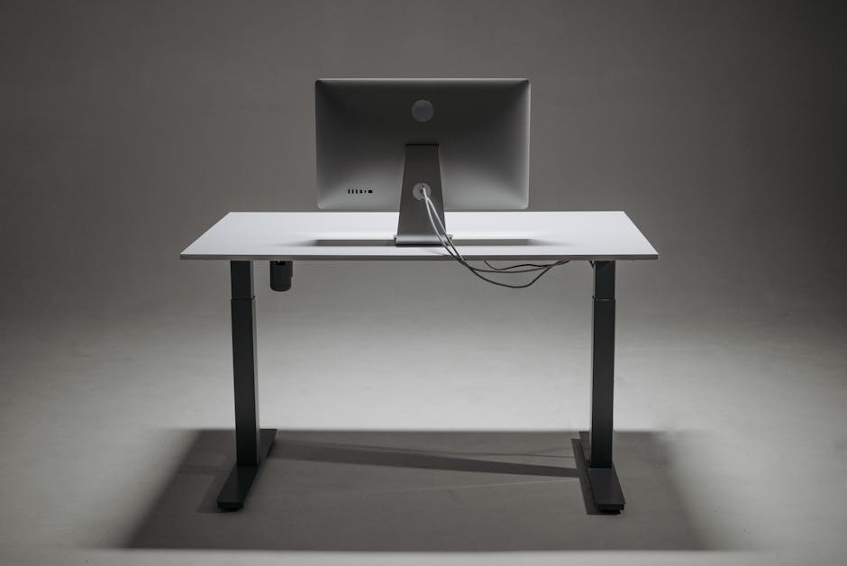 A minimalist setup featuring a standing desk and a computer monitor. The desk is clean and modern with a single monitor placed centrally, showcasing a simple and efficient workspace.