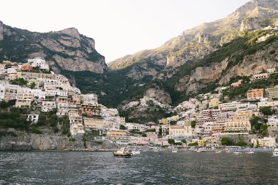 The image shows a picturesque coastal town with colorful buildings built into steep cliffs, overlooking the sea, likely Positano, Italy.