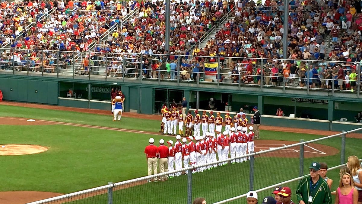 野球場で喜ぶリトルリーグ日本代表チーム。赤い横断幕を掲げ、2024年世界大会出場支援を募る選手たち。
