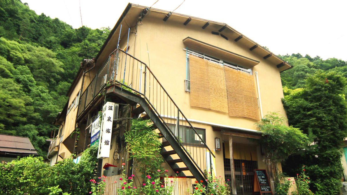 下部温泉の温泉宿にある岩造りの露天風呂。青々とした木々やシダに囲まれ、静かで落ち着いた雰囲気。