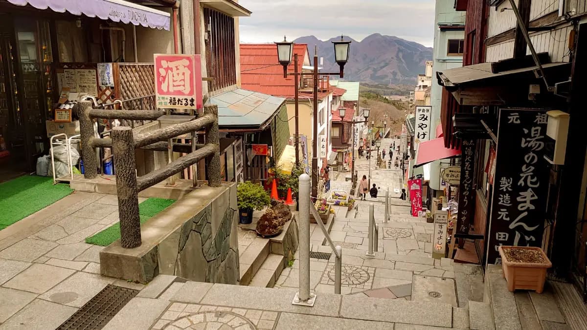 浴衣姿の男女が夕暮れ時の関東の温泉街を散策し、伝統的な木造旅館が並ぶ風情ある通りを歩きながら、温泉地ならではの旅のひとときを満喫している様子。