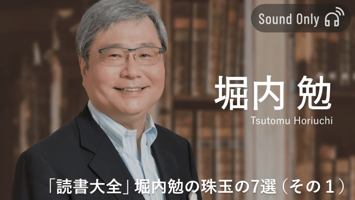 両手で本を開き、読書で知識を深める人のクローズアップ。暖かい光の中で集中し、背景には多くの本が並ぶ本棚が見える。
