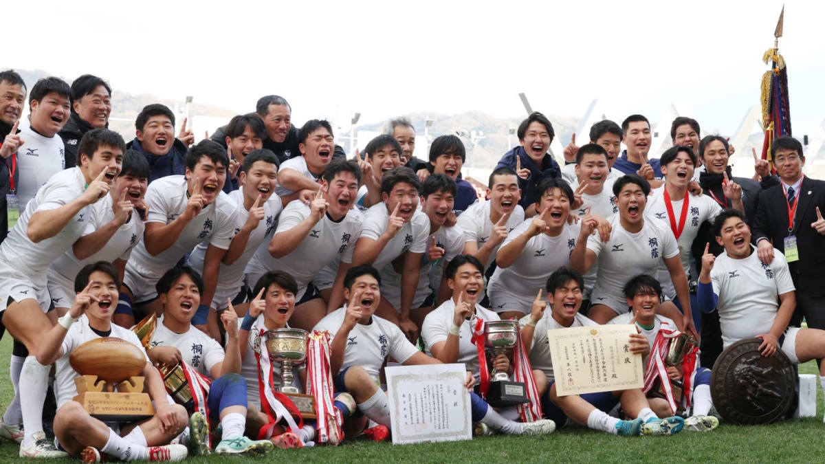 強豪校の選手が激しくぶつかり合う全国高校ラグビー大会の試合。青白ジャージの選手が相手にタックルする熱戦の瞬間。