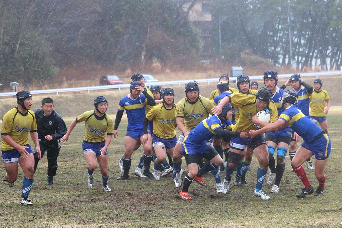 全国高校ラグビー抽選会で、黒い学ラン姿の選手たちが番号14の札を手に、緊張した表情で激戦ブロックの組み合わせ結果を見つめる。