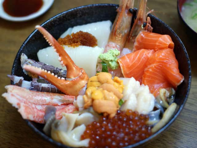 A classic 海鮮丼 explaining the dish, with vibrant tuna, salmon, shrimp, and shimmering ikura arranged over sushi rice.