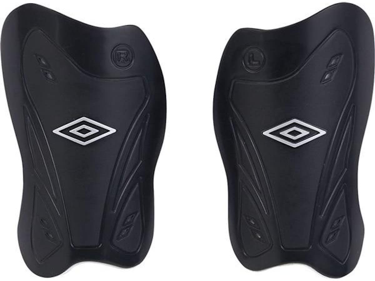 青いユニフォームの少年がサッカーボールに座り、白いソックスの上からキッズ用すね当てを装着。自分に合う種類を選ぶ場面。