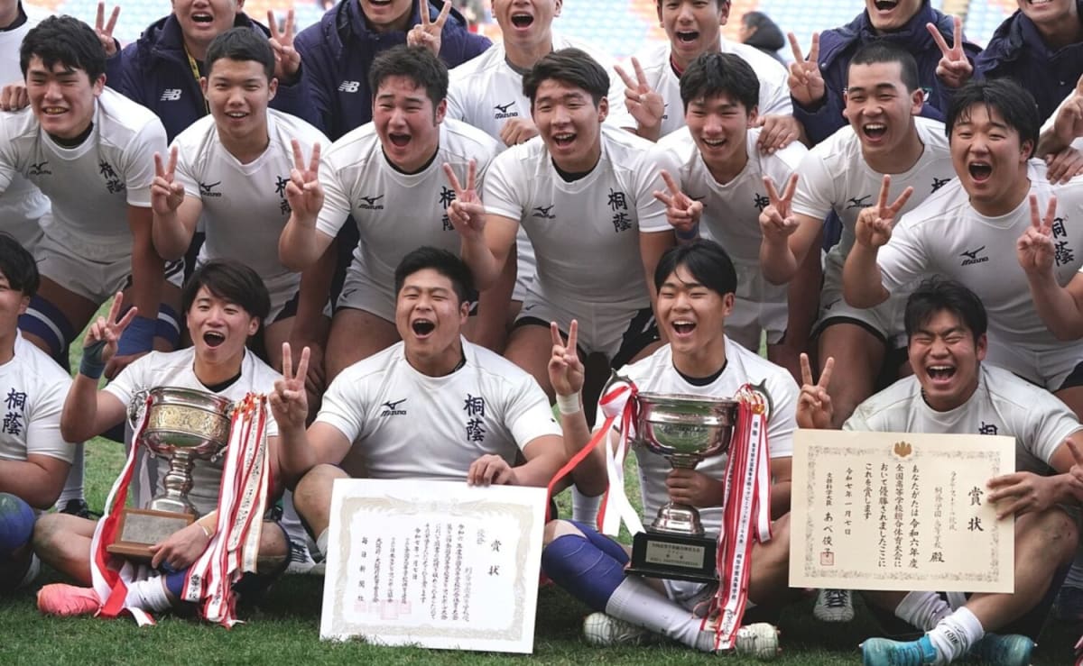 強豪校の高校ラグビー選手たちが黒と黄色のジャージで円陣を組む。花園を目指すチームの団結力と進路選択の熱意を示す。