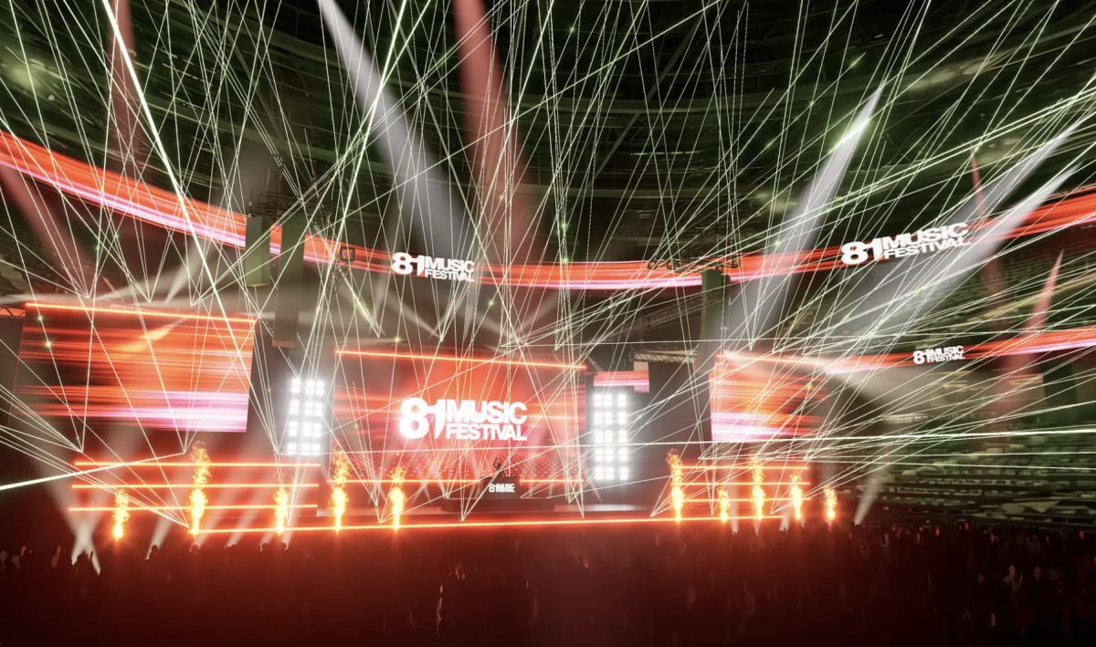 紫とピンクの照明が輝く夜の音楽フェスティバルで、2026年の東京開催を前に、大勢の観客が一体となり次世代アーティストのステージに向かって腕を上げ熱狂している。