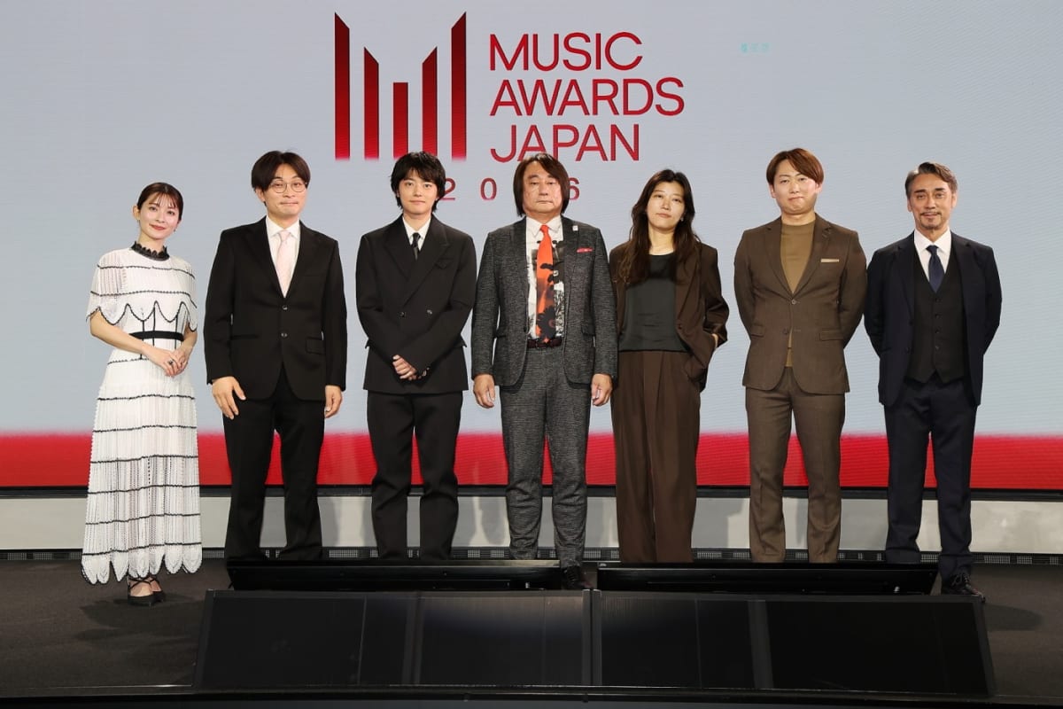 黒いジャケット姿の櫻井海音さんが、『MUSIC AWARDS JAPAN 2026』のロゴを背に、記者発表会でマイクの前に立ちスピーチする。