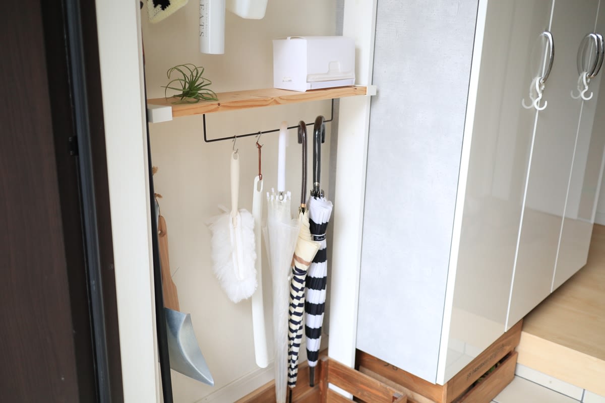 A person in a blue plaid shirt uses a drill to install a wooden LABRICO shelf bracket on a wall for a tidy entryway.