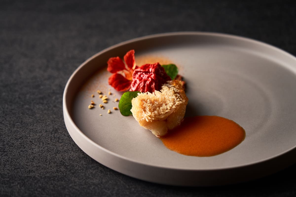 黒いお盆に美しく配膳された懐石料理。焼き魚、ご飯、蓋付きの汁物が並び和食マナーを示す。