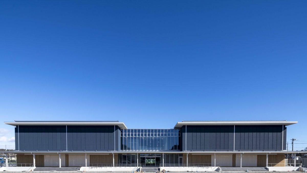 矢板市文化スポーツ複合施設のモダンな外観。青空の下、ガラス張りの壁と角ばった屋根が特徴的なスポーツ複合施設の全景。