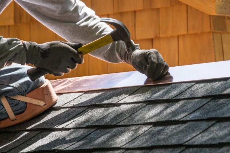 Roofer installing new flashing around a chimney