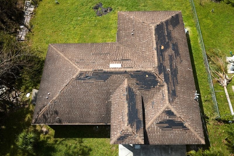 Roofer inspecting storm damage on shingles