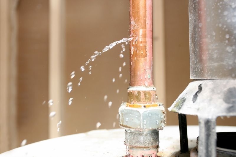 Plumber replacing a leaking pipe under a sink