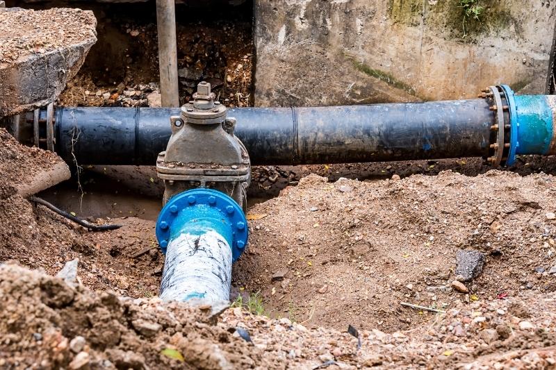 Plumber working on a main sewer line repair outside a home