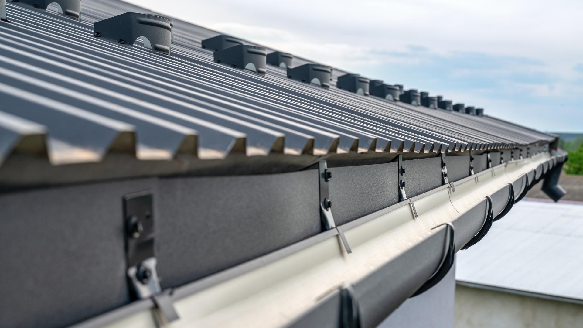 Technician cleaning gutters and checking roof ventilation