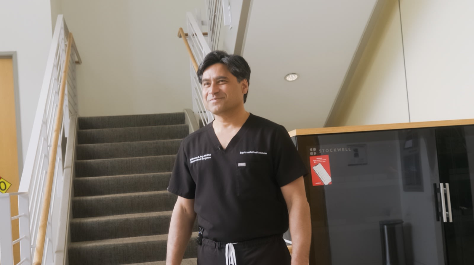 Dr. Ray in scrubs on the stairs between floors at a BARA office.