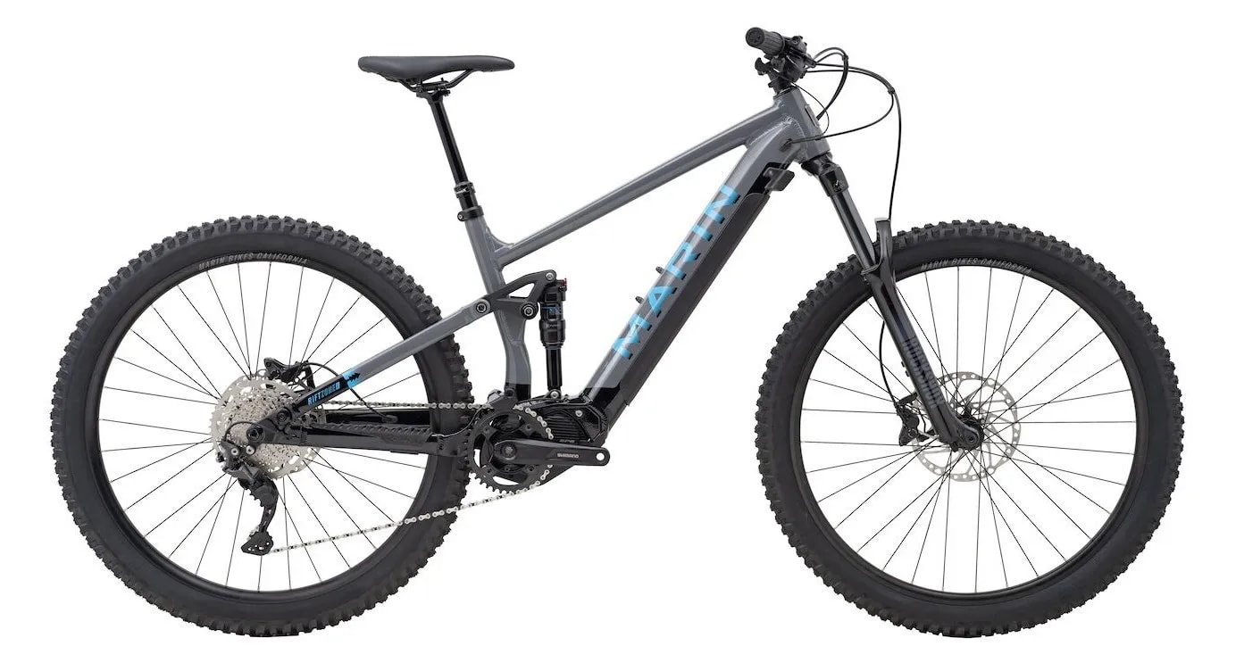 A black and gray mountain bike with thick tires and disc brakes, featuring a full suspension frame.
