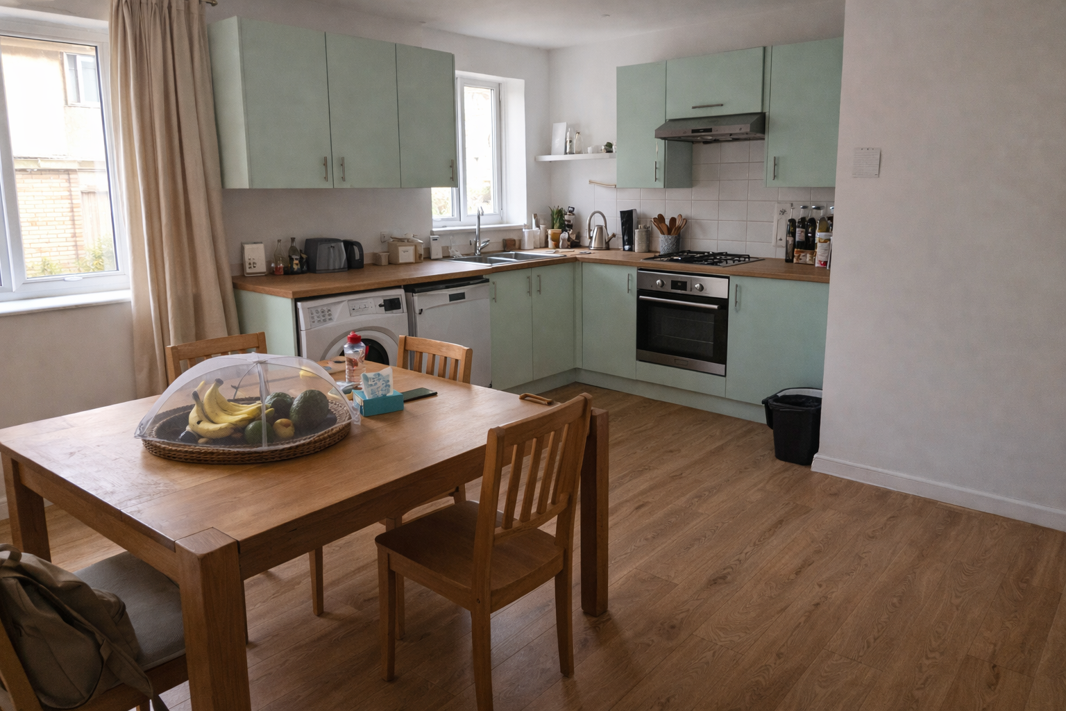 Pastel green kitchen in Runda with darker oak flooring installed