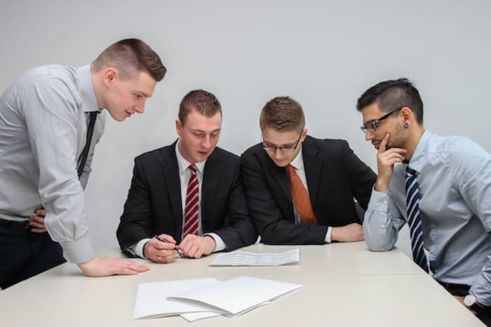 4 men doing paperwork