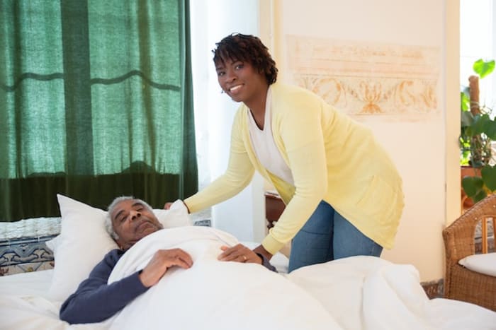 a girl looking after a old sick man in a bed
