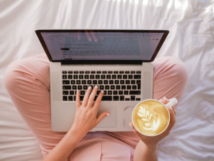 a girl using a laptop with coeffee in her hand