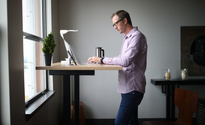 a man working on a standing desk with his laptop