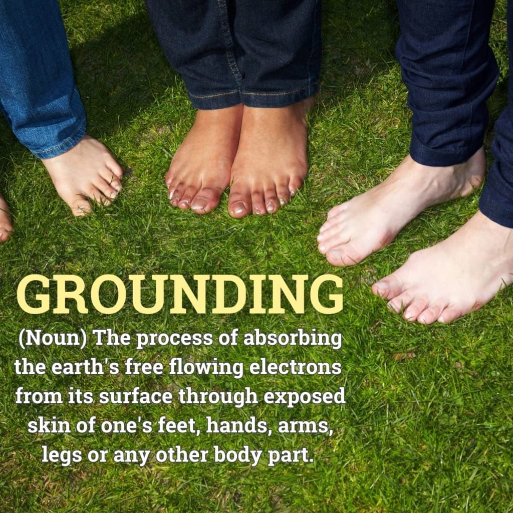 personnes aux pieds nus sur l'herbe avec la définition superposée de la mise à la terre en termes de terre et d'électrons