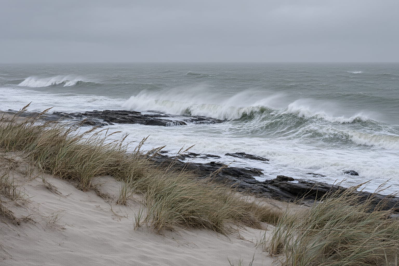 Heavy swell breaking white over a shallow rock reef beneath a low grey sky — illustrative of the sea conditions over the Agulhas Bank.