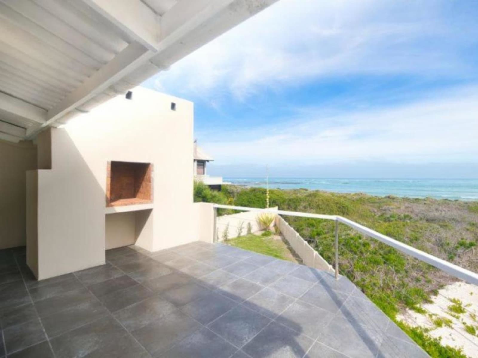 The covered balcony at Gans-te-Ver — slate tiles, a built-in braai and an uninterrupted view over the nature reserve to the sea.