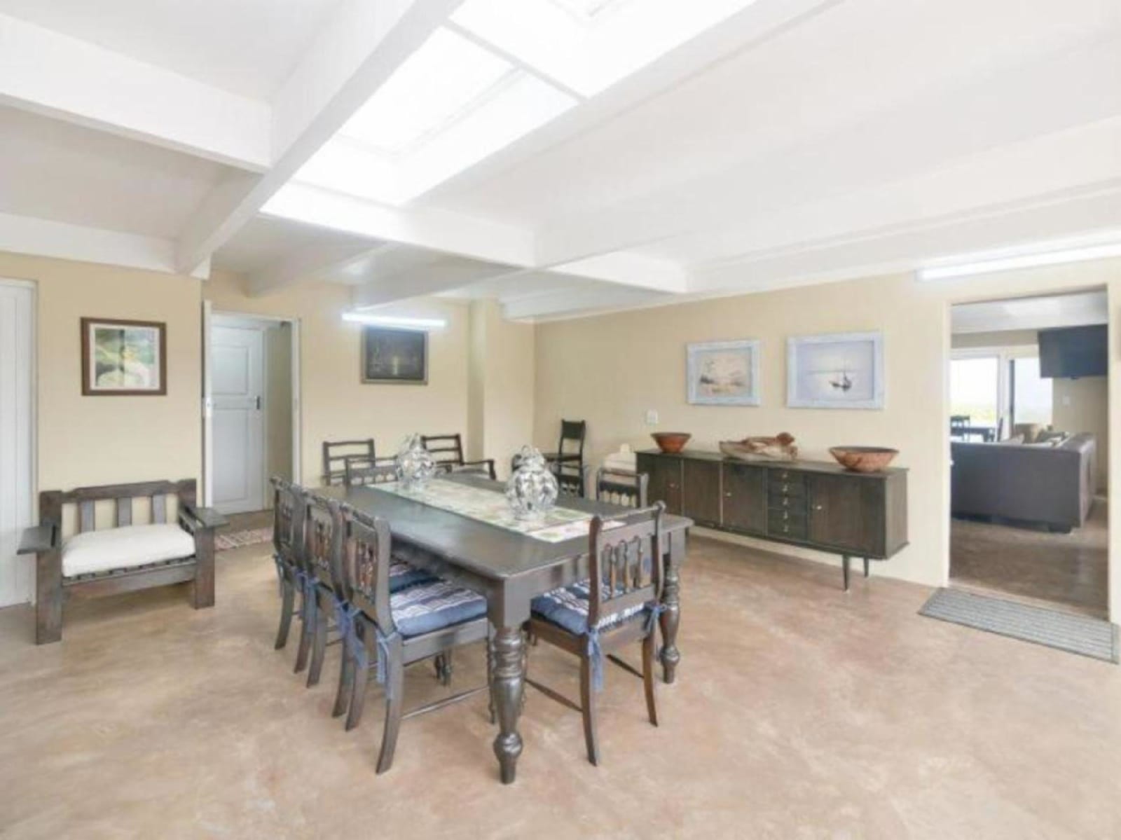The dining room at Gans-te-Ver under skylights — an eight-seater dark-wood table with a sideboard, off the open-plan living area.
